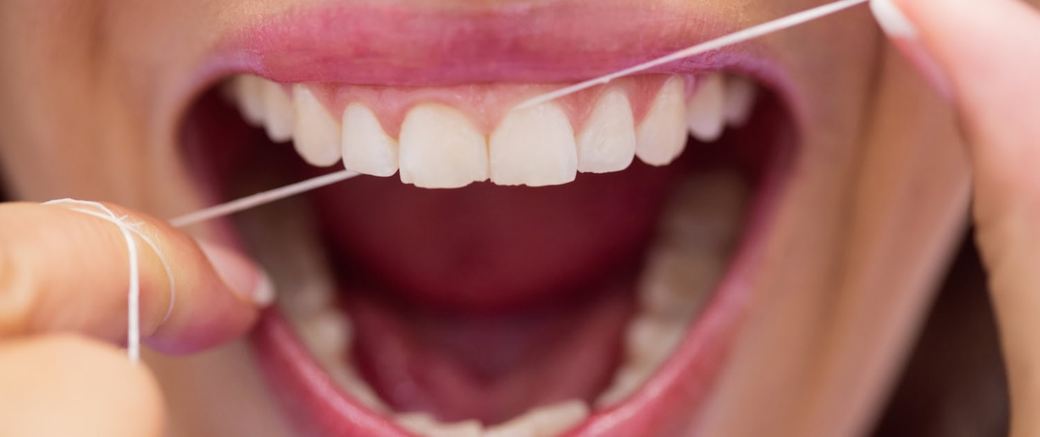 Close-up of female patient flossing her teeth in dental clinic
