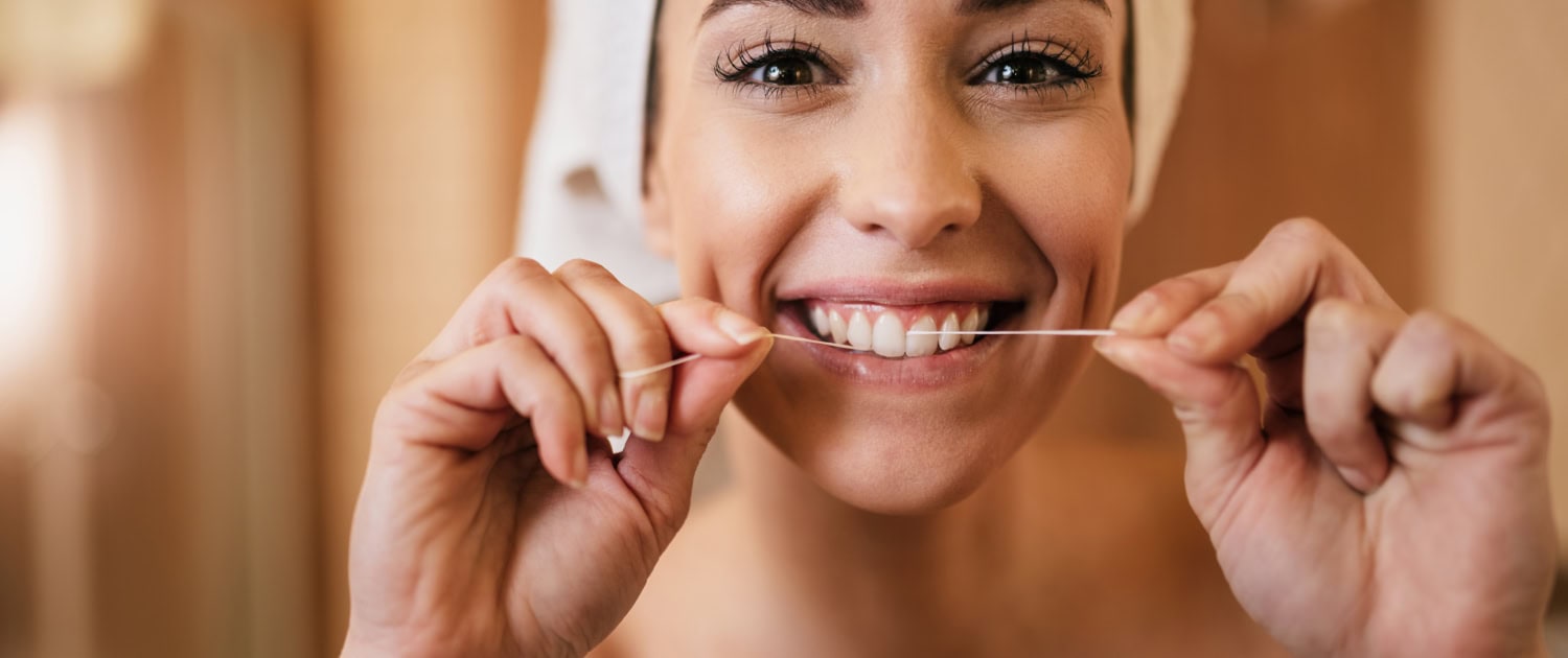 Beautiful woman using dental floss and cleaning her teeth in the