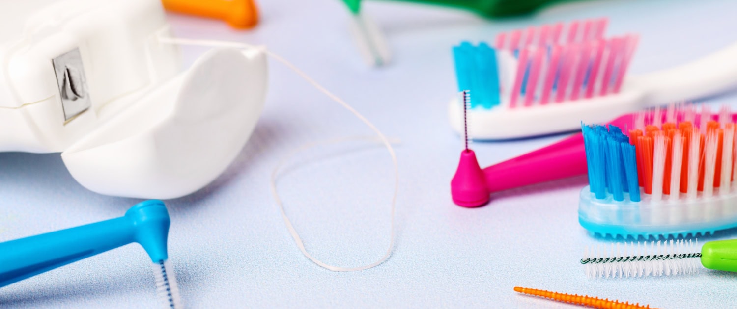 Different toothbrushes and dental floss on blue, close up.