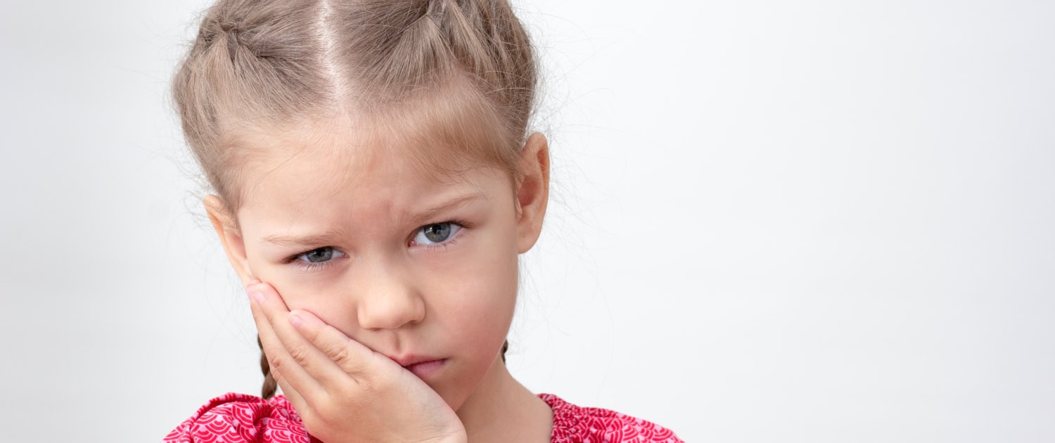 Serious child holding hand on cheek feeling ache